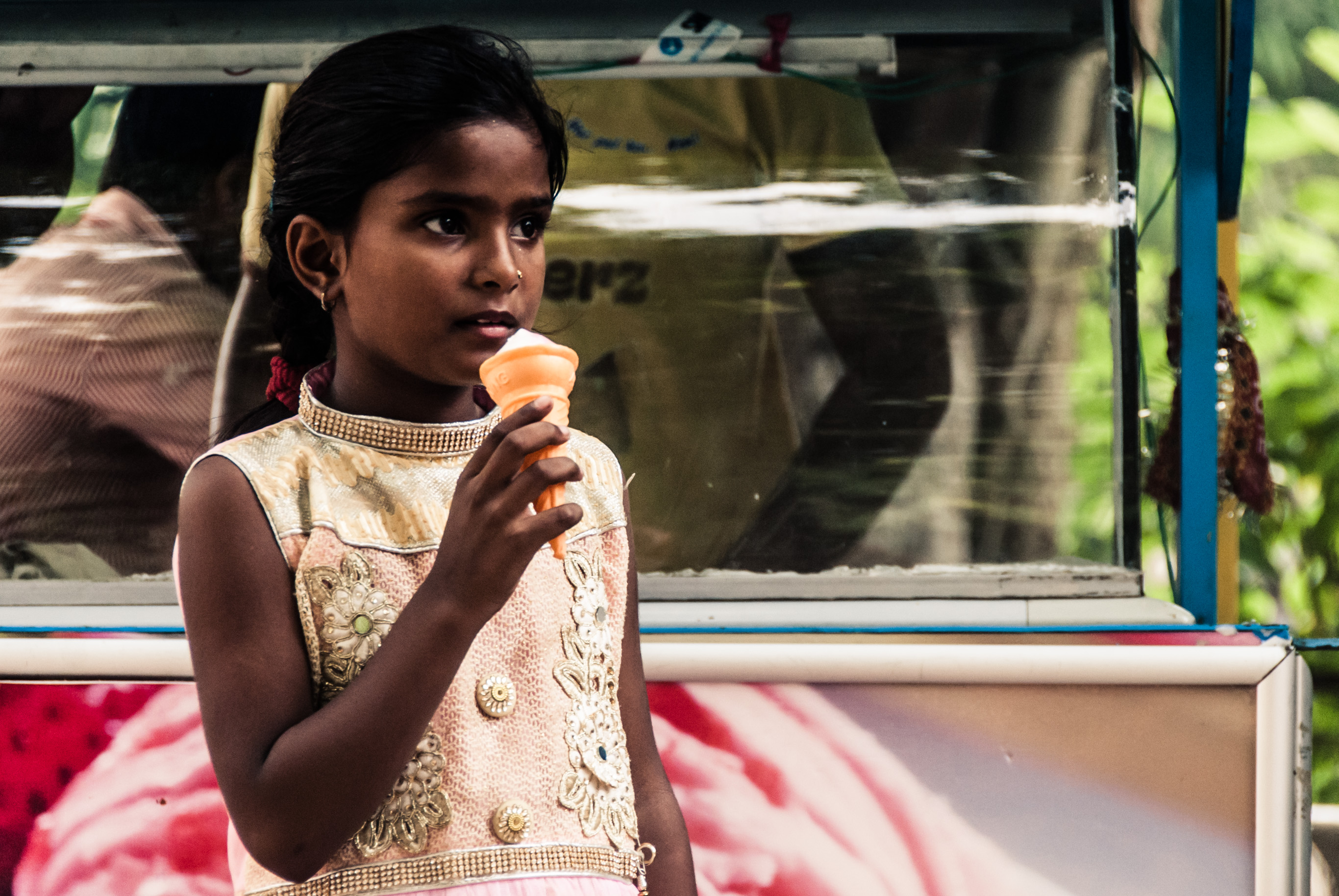 Une fillette mange une glace devant un chariot de vendeur