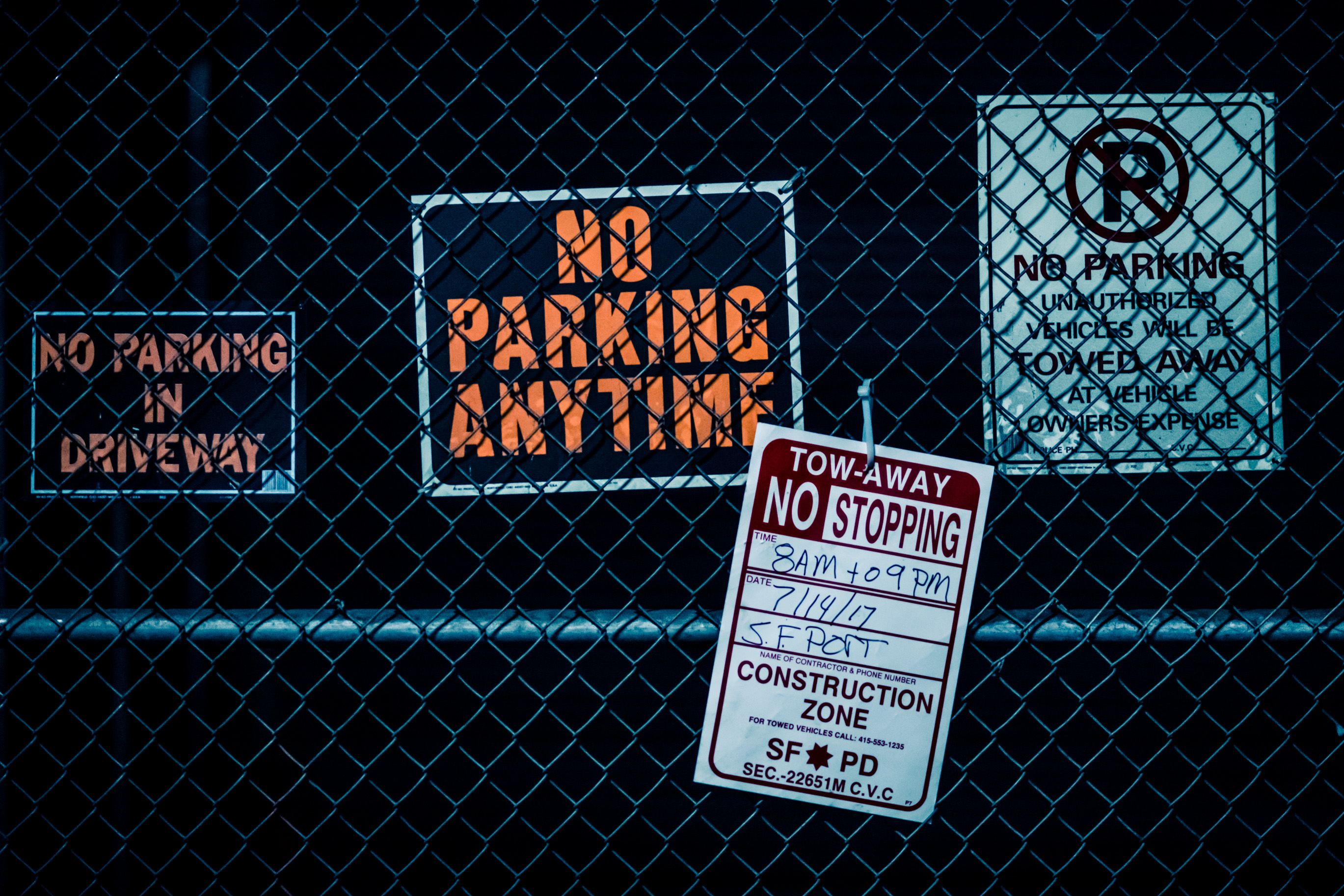 Un grillage couvert de panneaux « NO PARKING » et d'un avis « TOW-AWAY NO STOPPING »
