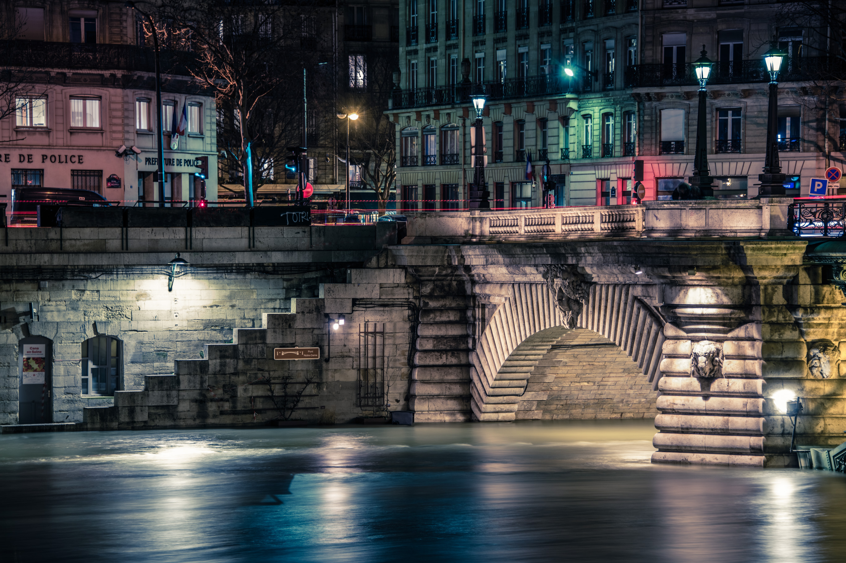 Un pont de pierre et un escalier de quai, de nuit, lampadaires allumés
